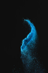 Wall Mural - close up of blue sand thrown in the air and copy space on black background