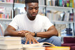 African student reads books in the library, preparing for exams.