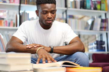 african student reads books in the library, preparing for exams.