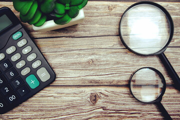 Workplace with magnifying glass and calculator top view on wooden background, Concept business and finance