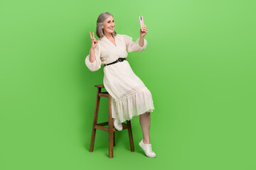 Poster - Full length photo of adorable sweet woman dressed beige outfit showing v-sign recording vlog device isolated green color background