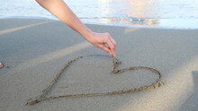 Woman Drawing Heart Shape On Sea Sand