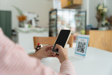 Wall Mural - Woman use smartphone to scan QR code for order menu in cafe restaurant with a digital delivery. Choose menu and order accumulate discount. E wallet, technology, pay online, credit card, bank app.