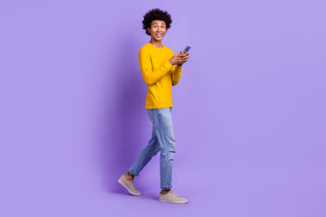 Wall Mural - Full size photo of impressed guy dressed yellow long sleeve denim pants hold smartphone staring isolated on purple color background