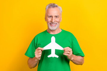 Poster - Photo of good mood cute man wear green t-shirt holding white paper plane card isolated yellow color background