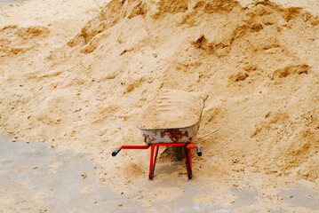 Construction equipment for transport of goods wheelbarrow near a pile of sand outdoors