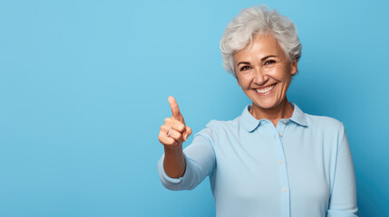 Senior woman standing over isolated blue background doing happy thumbs up gesture with hand.