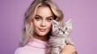 © Studio Nova - Woman holds a kitten in her arms on purple background.