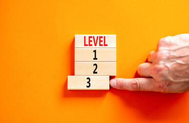 Time to level 3 symbol. Concept word Level 1 2 3 on wooden block. Businessman hand. Beautiful orange table orange background. Business planning and time to level 3 concept. Copy space.