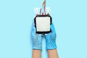 Female doctor with blood pack on blue background. World Donor Day