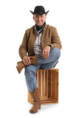 Wall Mural - Mature cowboy sitting on white background