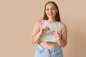 Wall Mural - Young woman opening condom on beige background