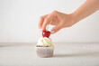 © Pixel-Shot - Woman decorating tasty cupcake with cherry on light background