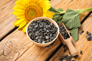 Wall Mural - Beautiful sunflower and bowl with seeds on wooden background