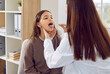 Back view of doctor otolaryngologist examining teenage girl patient's throat in medical office during checkup. Doctor woman pediatrician exam the oral cavity of a sick child in examination room.