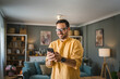 © Miljan Živković - One adult man with eyeglasses stand at home use mobile phone