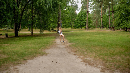 Wall Mural - Little boy holding rope while riding down the zip line at park. Kids sports, summer holiday, fun outdoors, scouts.