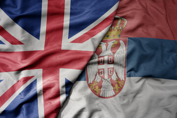 big waving national colorful flag of great britain and national flag of serbia .