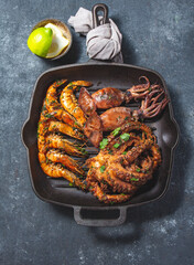 Wall Mural - Grilled spimps, squids and octopus in cast iron grill pan