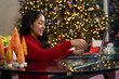 © SuperStock - Hispanic woman holding credit card in her right hand while online shopping on her computer in front of her Christmas tree at home