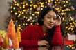 © SuperStock - Hispanic woman learning on her left hand in front of her Christmas tree at home