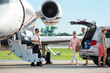 © SuperStock - Pilot greeting extended family for boarding of private plane for family vacation
