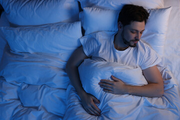 Wall Mural - Man sleeping in bed at night, above view. Space for text