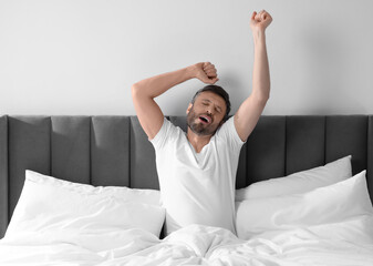 Sticker - Sleepy man stretching in soft bed at home in morning