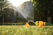 Automatic sprinkler watering green grass on sunny day in garden. Irrigation system