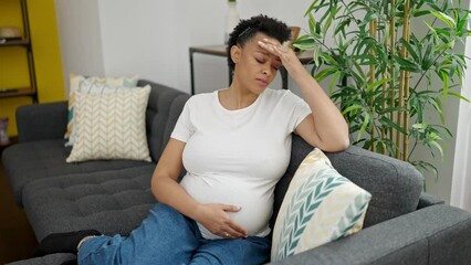 Wall Mural - Young pregnant woman sitting on sofa suffering for headache at home