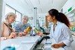 © Drazen - Happy senior couple buying vitamins with help of female pharmacist in drugstore.