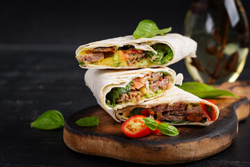 Wall Mural - Grilled tortilla wraps with beef and fresh vegetables on wooden board. Beef burrito. Mexican food. Healthy food concept.