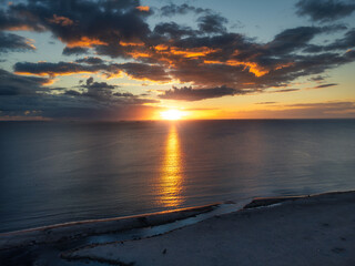 Sunset clouds above the sea horizon with Jelitkowo beach at the bottom of the landscape.  Aerial, drone view.