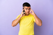 © luismolinero - Young handsome man using mobile phone over isolated purple background thinking an idea