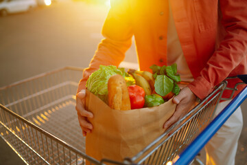 Wall Mural - Young man with a bag full of groceries, in a car. Grocery delivery man prepares fresh vegetable delivery service. Healthy lifestyle.