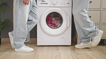 Wall Mural - Two men couple waiting for washing machine standing at laundry room