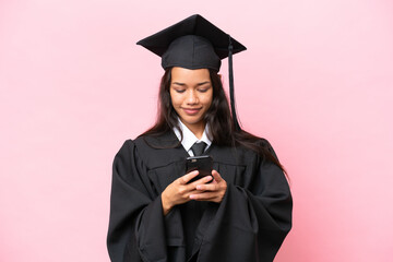 Wall Mural - Young university Colombian woman graduate isolated on pink background sending a message with the mobile