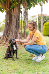 Wall Mural - Young blonde woman with her adorable black dog at outdoors