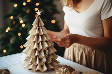 young woman making paper christmas tree decoration at home.