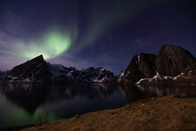 Amazing View Of Northern Lights Over Snowy Mountains In Dark Night