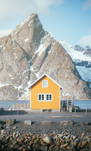 Yellow Wooden Cabin With Fencing In Daylight Near Snowy Mountain