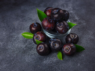 Wall Mural - Sweet plums on dark background. Fresh blue plums with leaves. Food fruit Background. Summer postcard. Harvesting in garden, Harvest of plum