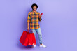 Full body photo of youngster man wear plaid trendy shirt jeans hold red bargains shopaholic ecommerce ad isolated on violet color background