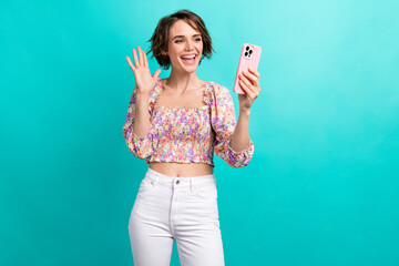 Poster - Portrait of positive girl with bob hairdo dressed flower print blouse talking on smartphone video call isolated on teal color background