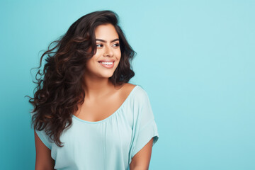 Wall Mural - plus sized Latina woman smiling on a blue background studio shot