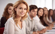 © visoot - Attractive young woman smiling at the seminar with other people sitting behind her in a row.