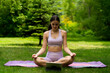 © Mihail - young girl on a grass field doing an online yoga class on a mat