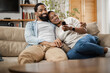 © Goran - Happy African American couple watching TV on sofa in the living room