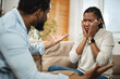 © Goran - Angry African American couple arguing on sofa in the living room