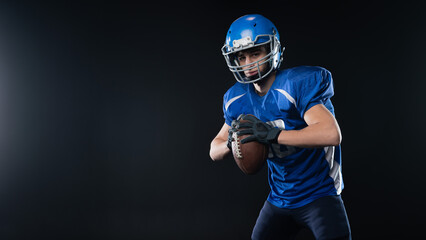 Portrait of a man in a blue uniform for american football on a black background. 